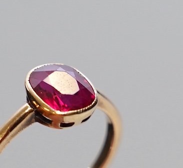 A yellow metal and single stone oval cut synthetic ruby set ring, size L, gross weight 2 grams. Condition - good